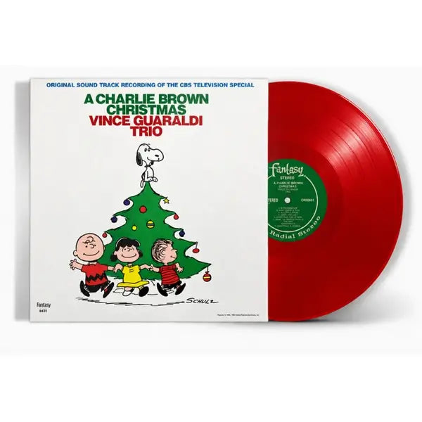 Vinyl record album cover for 'A Charlie Brown Christmas' by Vince Guaraldi Trio, shown with a red translucent vinyl record partially pulled from the sleeve. The cover features Peanuts characters and a Christmas tree on a white background.