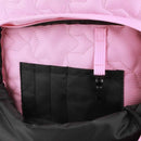 Close-up of a pink quilted bag with a black pocket