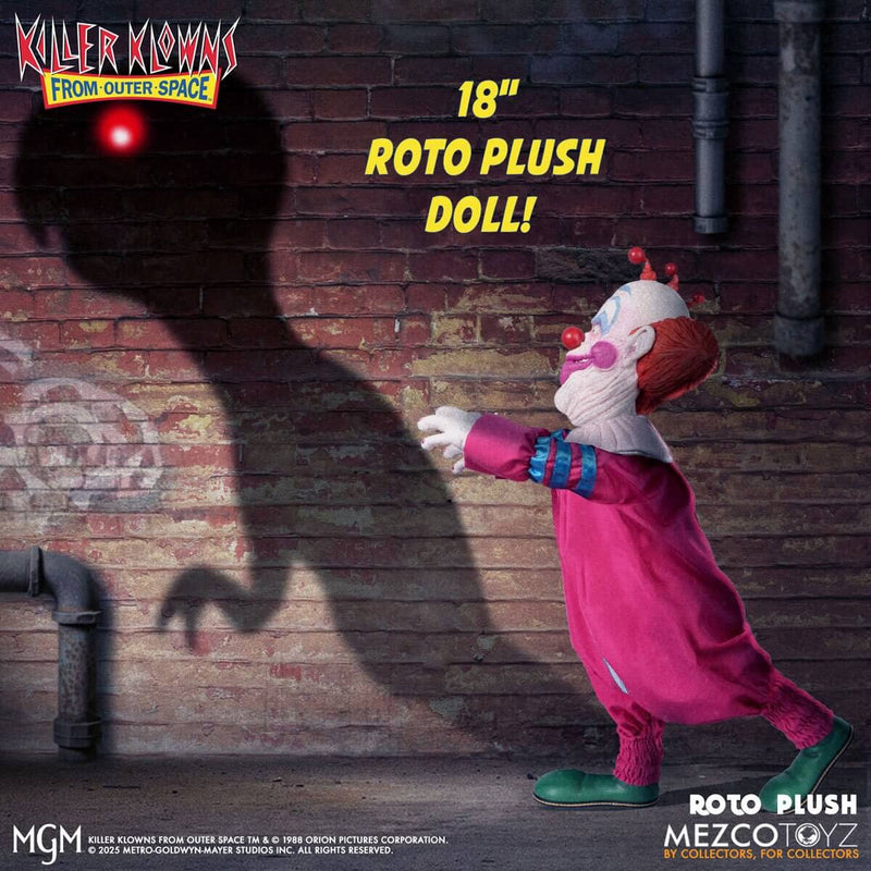 Roto plush doll from Killer Klowns from Outer Space with red light on head against a brick wall.