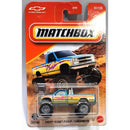 Matchbox Chevrolet K1500 Pickup die-cast toy car in its original blister packaging, featuring a blue and yellow truck with orange flames on a desert-themed cardback.