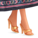 Close-up of a doll's feet wearing gold high-heeled shoes on a white background