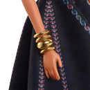 Close-up of a doll's hand wearing gold bracelets on a dark fabric background