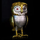 A Bubo owl figurine with a metallic gold and silver finish, featuring large round white eyes with red centers, standing against a solid black background.