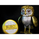 A collectible Bubo owl figurine by Ray Harryhausen, featuring a metallic gold and silver body with blue-tinted eyes, shown next to its circular gold and silver Bubo collectible capsule on a black background.