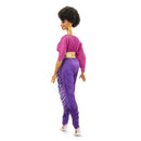 Doll wearing a pink top and purple fringed pants on a white background