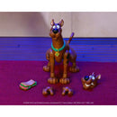 Scooby-Doo action figure set on a purple textured surface with a blue-striped backdrop. The set includes a standing Scooby figure with a teal collar, a head-piece, a sandwich accessory, and two detached legs.