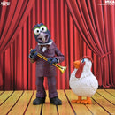 Muppet action figure of Gonzo holding a gold trumpet next to a white chicken figure, set against a red stage curtain backdrop with wooden floorboards.