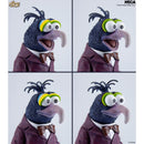 Four-panel close-up of a Muppet character figure wearing a burgundy suit, white shirt, brown bow tie, and yellow-and-green eyepatch, shown against a light gray background. NECA and Disney branding are visible.