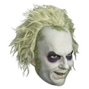 A Halloween mask of the character Beetlejuice, featuring pale skin with dark purple eye makeup, a wide grin, and messy, spiked blond hair with green moss details.