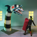 Beetlejuice in costume facing a large, sandworm creature head in a room with windows.