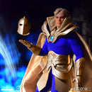 A collectible action figure of a blue-robed character with gold armor and a floating gold mask, photographed against a dark blue and black background with dramatic lighting. Visible logos at the bottom read One:12, DC, and Mezco Toyz.