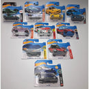 A collection of ten Hot Wheels toy cars in their original blister card packaging, arranged on a light gray surface.