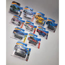 A collection of ten Hot Wheels toy cars in their original blister packaging, arranged on a light gray surface. 
