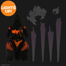 Toy figure of Godzilla with glowing orange and black design, standing next to three tall, thin objects on a dark background.