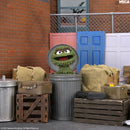 A Sesame Street Oscar the Grouch figure stands in a gray trash can, surrounded by burlap sacks, wooden crates. The NECA logo appears in the top right corner.