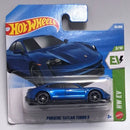 A Hot Wheels die-cast toy car of the Porsche Taycan Turbo S, presented in its original blister pack packaging. The toy car is metallic blue, and the backing card features the Hot Wheels logo, a large illustration of the blue car, and a green EV column indicator.