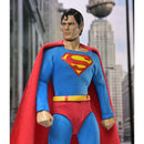 Superman action figure posed against a blurred cityscape background with skyscrapers and a globe.